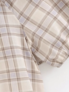 Close-up of beige plaid fabric texture and elastic cuff detail on women's blouse
