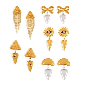 Detail van bohemien gouden oorbellen met oogmotieven, hartvormige hangers en kwastjes