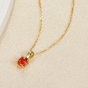 Detail of a 925 silver gold necklace with a round red zircon in a four-prong setting