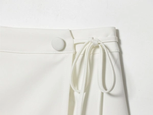 Detail of white blazer dress showing fabric texture, fabric-covered buttons and waist ties