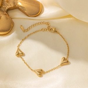 Polished gold stainless steel bracelet featuring three 3D heart charms on yellow silk