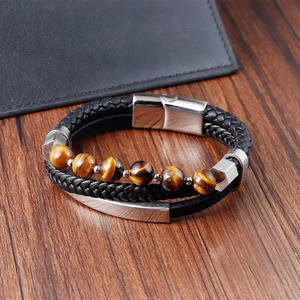 Detalle de pulsera de cuero trenzado multicapa con cuentas de ojo de tigre sobre madera