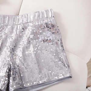Detailaufnahme der schimmernden silbernen Pailletten und des Gummibunds der Party-Shorts
