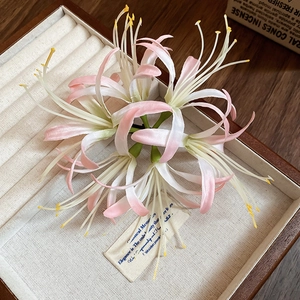 Detailed macro shot of a pink and white artificial lily hair clip in a wooden jewelry tray