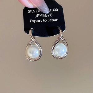 Détail macro de boucle d'oreille en argent avec perle blanche et design courbé