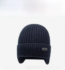 Detailed view of dark blue knitted winter hat with ear flaps and FBXS patch detail