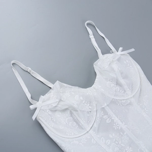 Détail de la dentelle florale blanche et du mesh délicat avec nœud sur la robe d'été