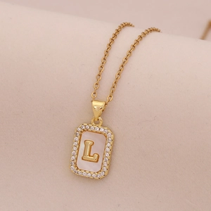 Gros plan du collier en or 18K avec pendentif nacre, lettre L et contour de diamants