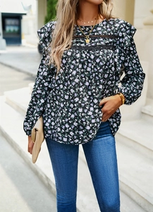 Detail shot of black floral blouse featuring ruffled shoulders and lace panels