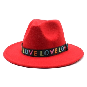 Détail d'un chapeau en laine rouge avec broderie LOVE arc-en-ciel sur ruban noir