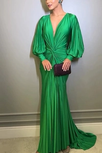 Detail of emerald green pleated dress with deep V-neck and luxurious satin fabric texture
