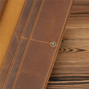 Macro detail of vintage brown crazy horse leather wallet with neat stitching and brass snap