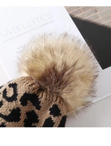 Close-up of leopard print knit beanie featuring a fluffy pompom and fine texture details
