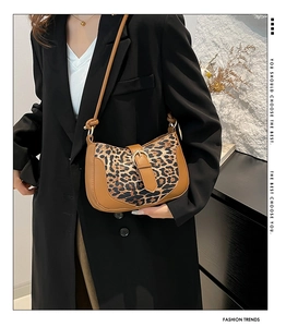 Detail of leopard print underarm bag with brown leather trim and golden metal buckle