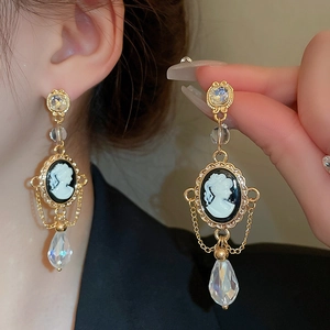 Detail of vintage cameo earrings with gold plating, black portrait, and crystal teardrop