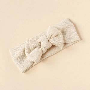 Close-up of soft beige waffle texture bow headband for infants with elastic fabric detail