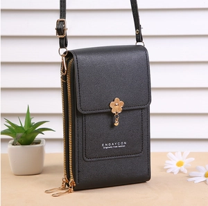 Close-up of black lychee grain leather crossbody bag with dual gold zippers and flower charm