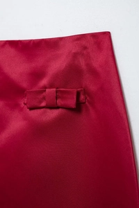 Detail of red satin fabric with elegant bow accent and smooth glossy texture finish