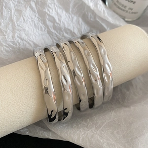 Detailed macro view of five silver-plated textured metal bangles and thick rings set