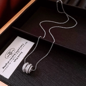 Macro detail of silver cylinder pendant with cubic zirconia on brown texture tray