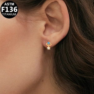 Detail showing G23 titanium stud earring with blue gemstone and star pendant charm
