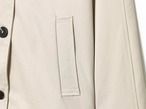 Dettaglio ravvicinato di un trench beige con bottoni neri e cuciture di alta qualità