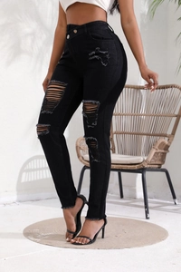 Détail du jean noir avec genoux déchirés et finitions effilochées de style mode urbaine