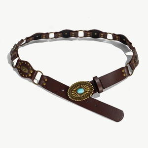 Dettaglio di cintura boho vintage con anelli in pelle marrone, borchie e fibbia turchese