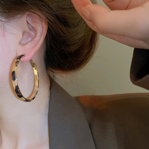 Close-up of leopard print hoop earrings on a model with a polished inner gold finish