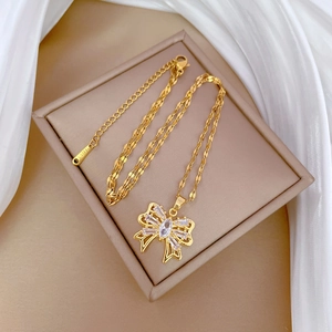 Detail of gold bow pendant with crystals on a wave chain showing S.STEEL hallmark