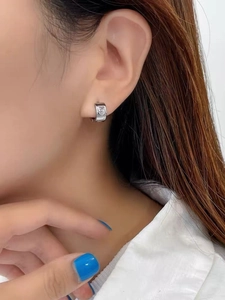 Close-up of silver huggie earring with heart-shaped zircon inlay worn by model