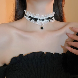 Detail of white lace choker featuring a black bow and heart pendant on model's neck
