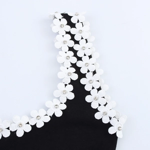 Detailed view of white lace floral accents with rhinestones on a black knit dress strap