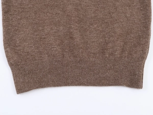 Gros plan détaillé du pull en tricot marron foncé montrant l'ourlet côtelé fin