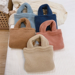 Détail de cinq couleurs de mini sacs à main en laine d'agneau dans un cadre chaleureux