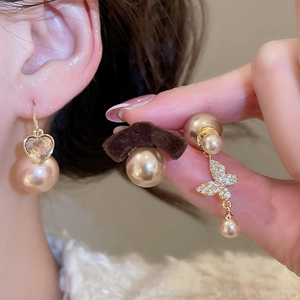Detailed close-up of zircon heart butterfly earrings and elegant pink pearls