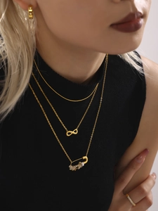 Détail d'un collier doré multicouche avec symbole infini et pendentif épingle serti de pierres