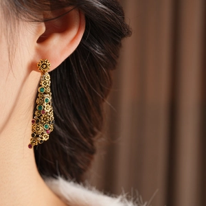 Gros plan de boucles d'oreilles fleurs vintage dorées avec pierres multicolores