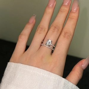 Macro shot of S925 sterling silver ring with emerald-cut gem on woman's finger