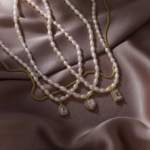 Close-up of three baroque rice pearl necklaces with gold zircon geometric pendants