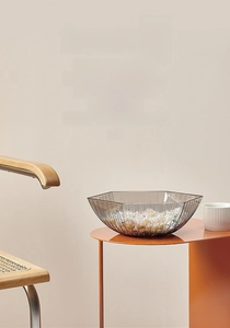 Close-up of a translucent grey hexagonal snack bowl on an orange side table