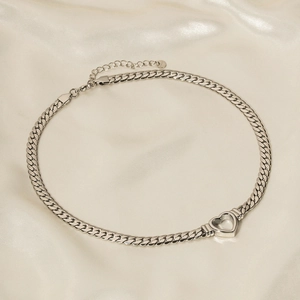 Silver stainless steel cuban link necklace with hollow heart pendant on beige silk