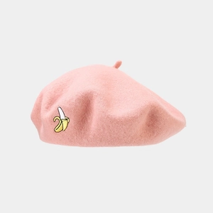 Close-up of a pink wool beret featuring detailed yellow banana embroidery on the side