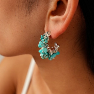 Bohemian C-shaped earrings with irregular turquoise beads on a silver base worn by model