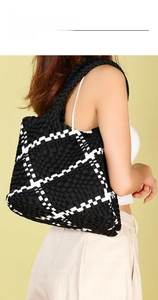 Close-up of a large black and white woven tote bag shown on a model with premium leather texture