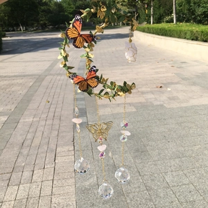 Detail of moon-shaped wind chime with pink quartz crystals and monarch butterflies