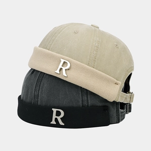 Dettaglio del cappello docker vintage con logo R in metallo, cotone lavato e bordo a coste