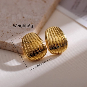 Macro view of gold seashell earrings with textured ridges on elegant stone background