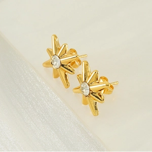 Macro shot of gold eight-point star earrings with zircon inlay on white silk