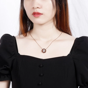 Détail du pendentif cœur en or rose avec incrustation de coquillages et cristaux sur cou